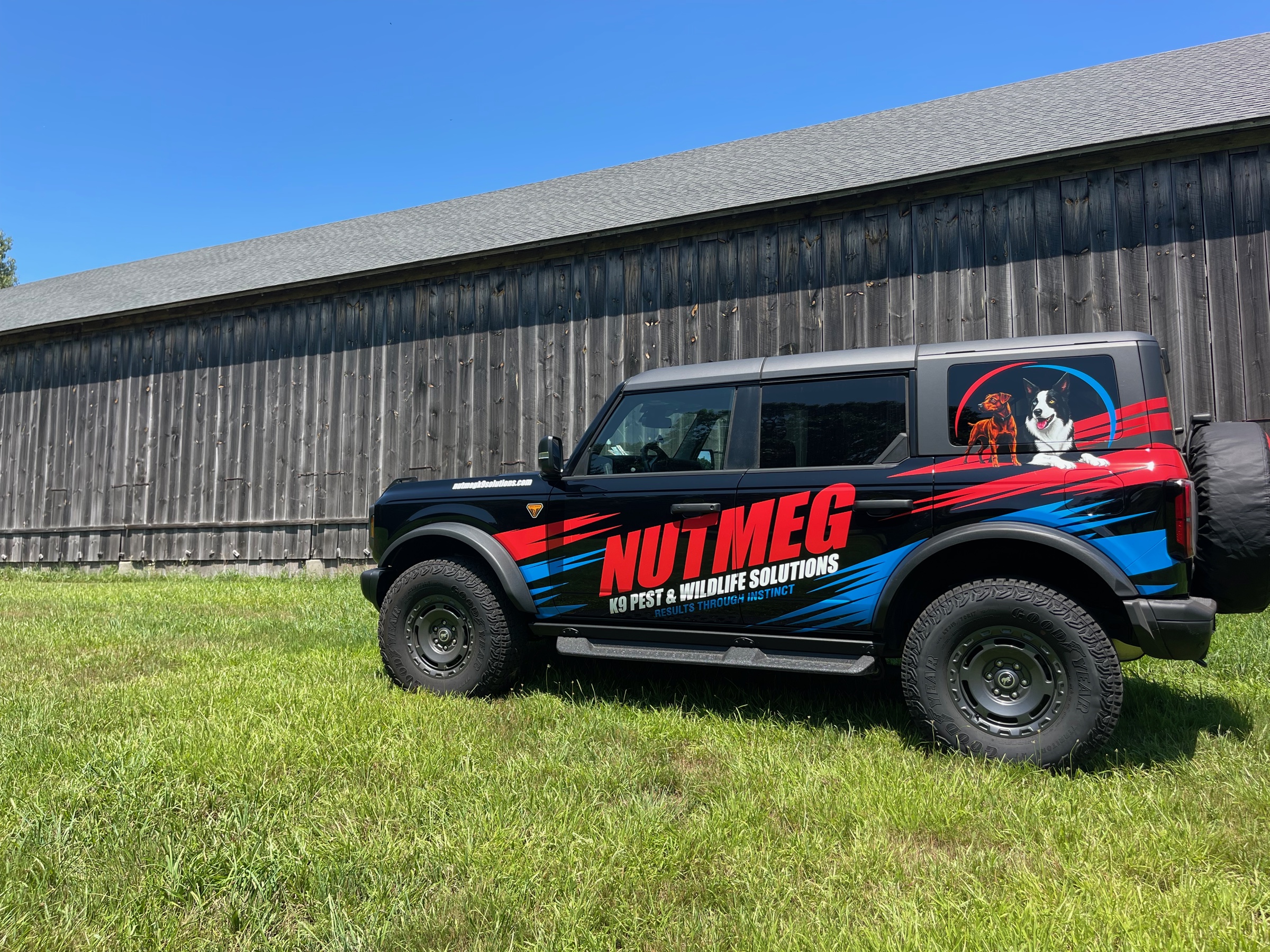 Nutmeg K9 Solutions wrapped Bronco parked beside a barn